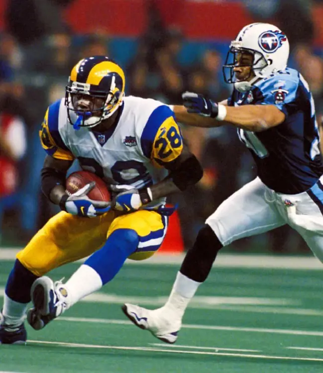 St Louis Ram's Marshall Faulk (right) runs with the ball in his hand while Titans' Georgia Dome follows during the 2000 Super Bowl.