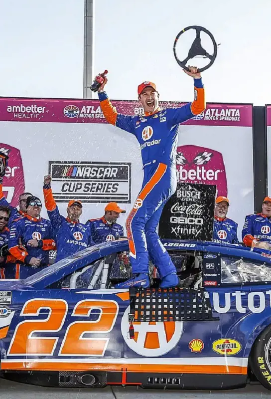 Joey Logano climbs on the side of his car to celebrate his 2023 victory.